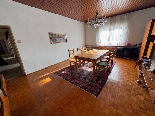 Klassisches Esszimmer mit Holztisch, Parkettboden, Kronleuchter und großen Fenstern.
