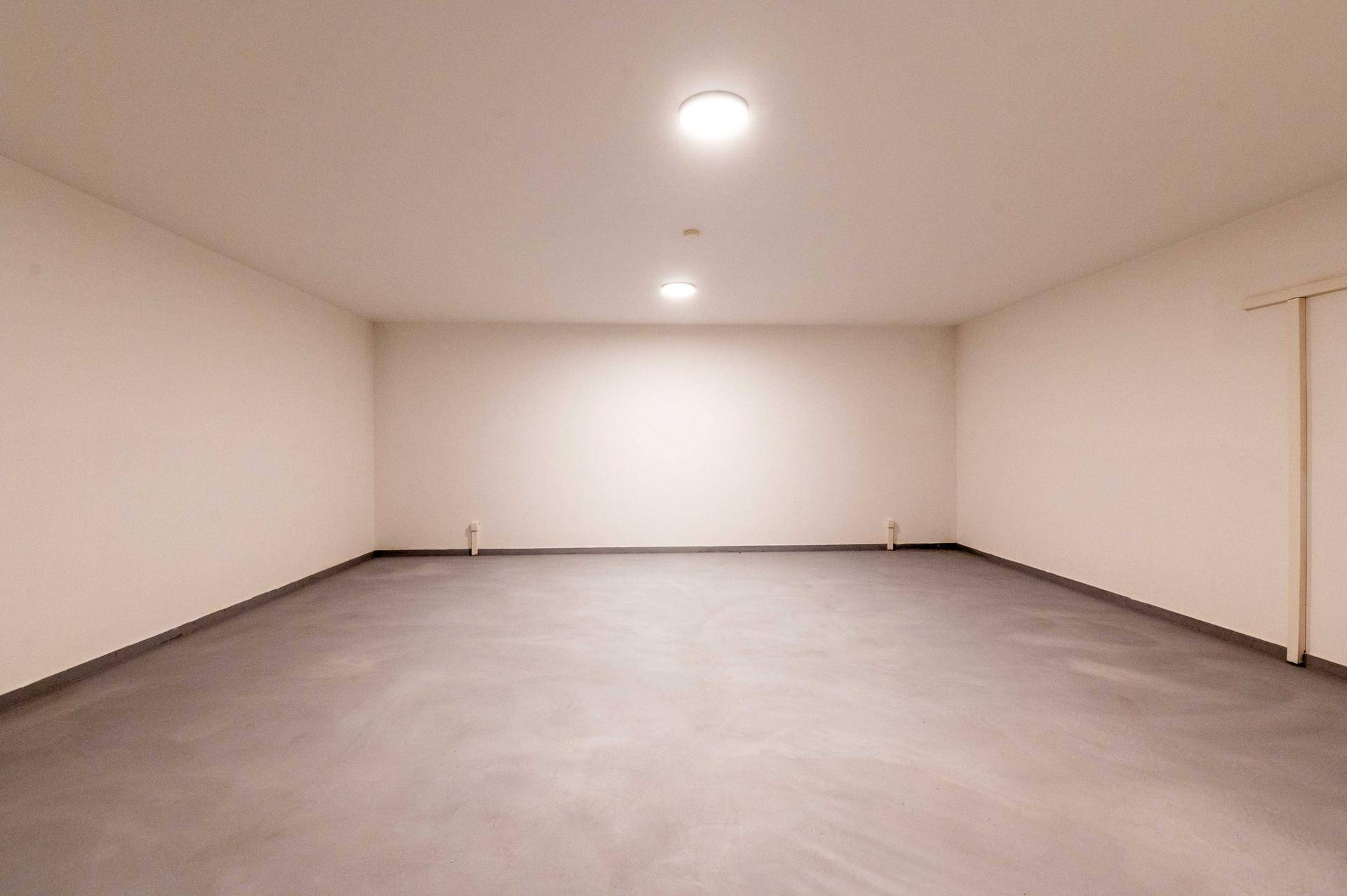 Heller Kellerraum mit glattem Boden und Deckenleuchten.
