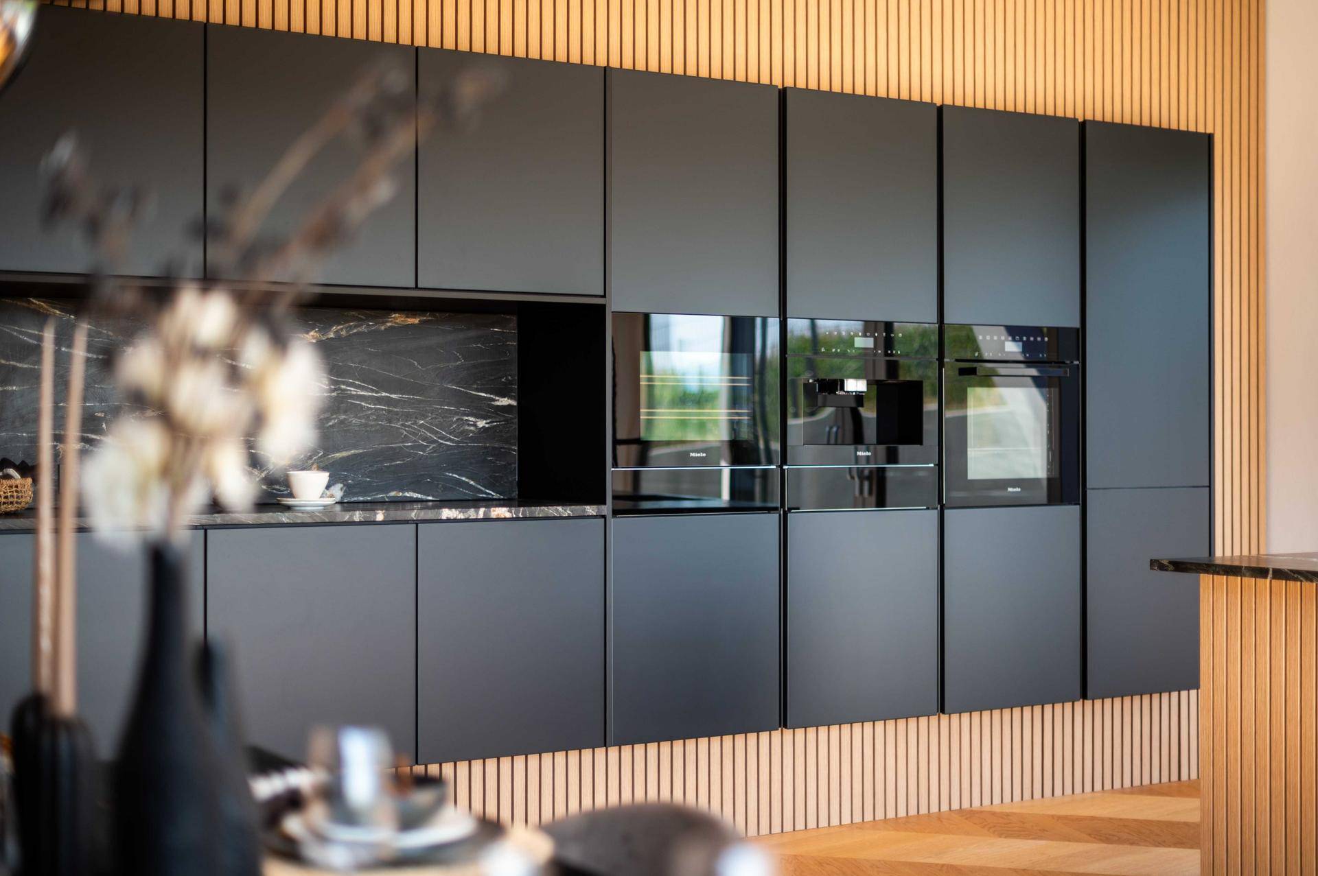 Hochwertige Miele-Einbaugeräte in der modernen schwarzen Küche.