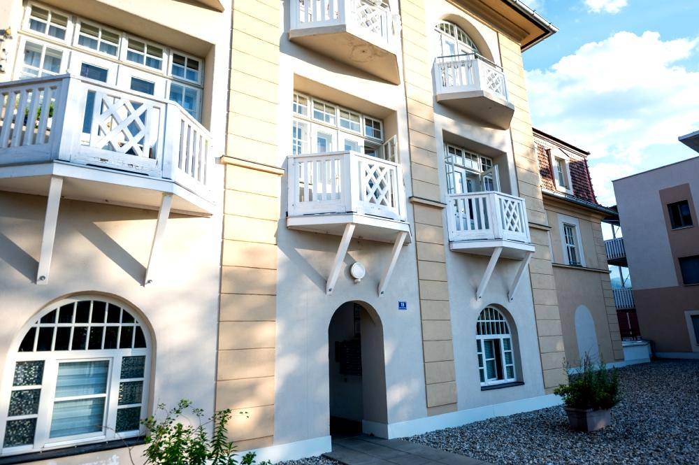 Detailansicht der historischen Fassade mit weißen Balkonen und Bogenfenstern.