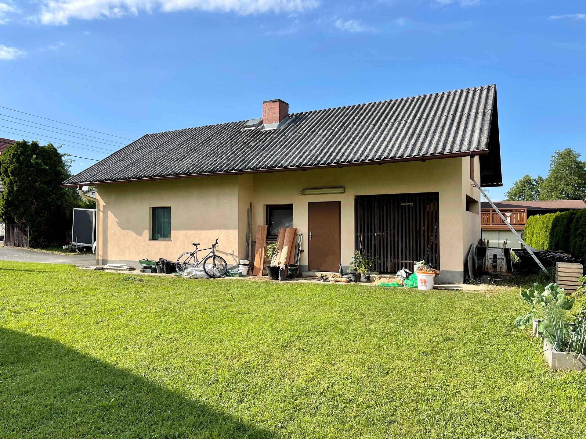 Nebengebäude mit Garage und Werkstatt, umgeben von einer grünen Rasenfläche.