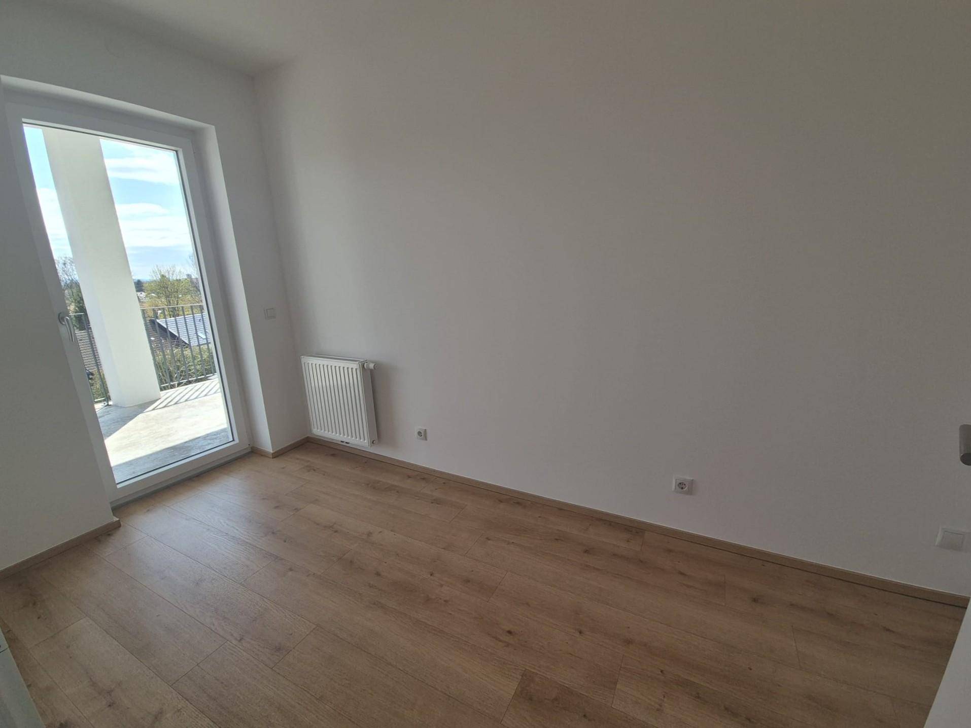 Lichtdurchflutetes Schlafzimmer mit Laminatboden und Zugang zu einem Balkon oder einer Terrasse.