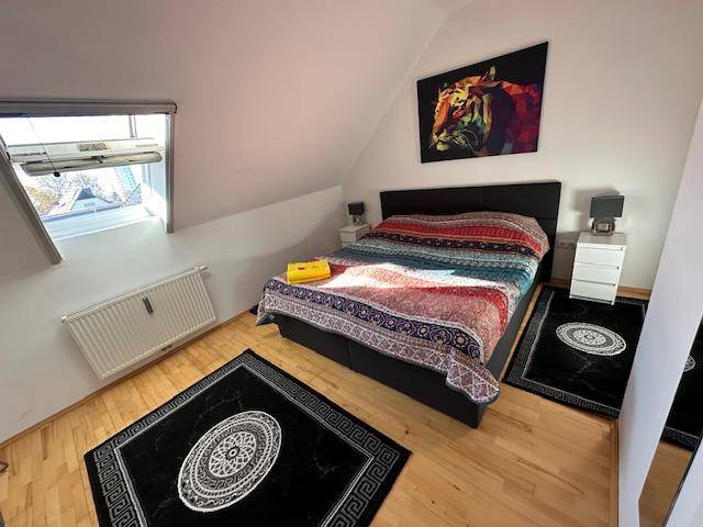 Gemütliches Schlafzimmer im Dachgeschoss mit Doppelbett, Dachfenster und farbenfroher Bettdecke.