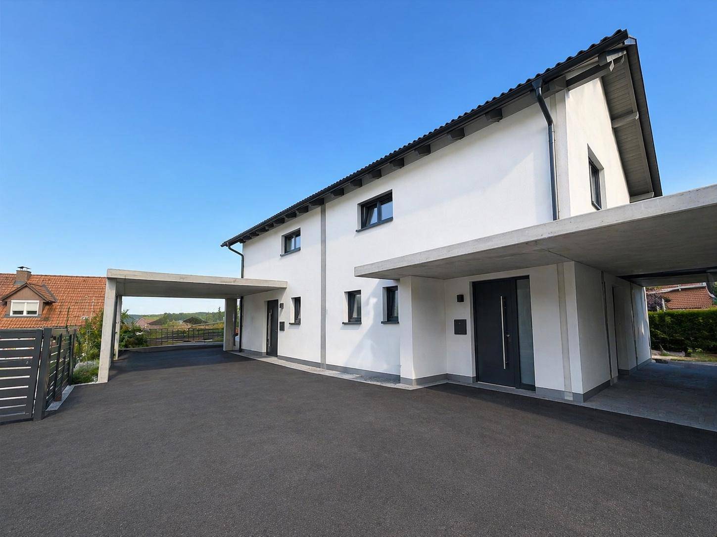 Vorderansicht der Doppelhaushälfte mit zwei Carports und modernem Eingangsbereich.