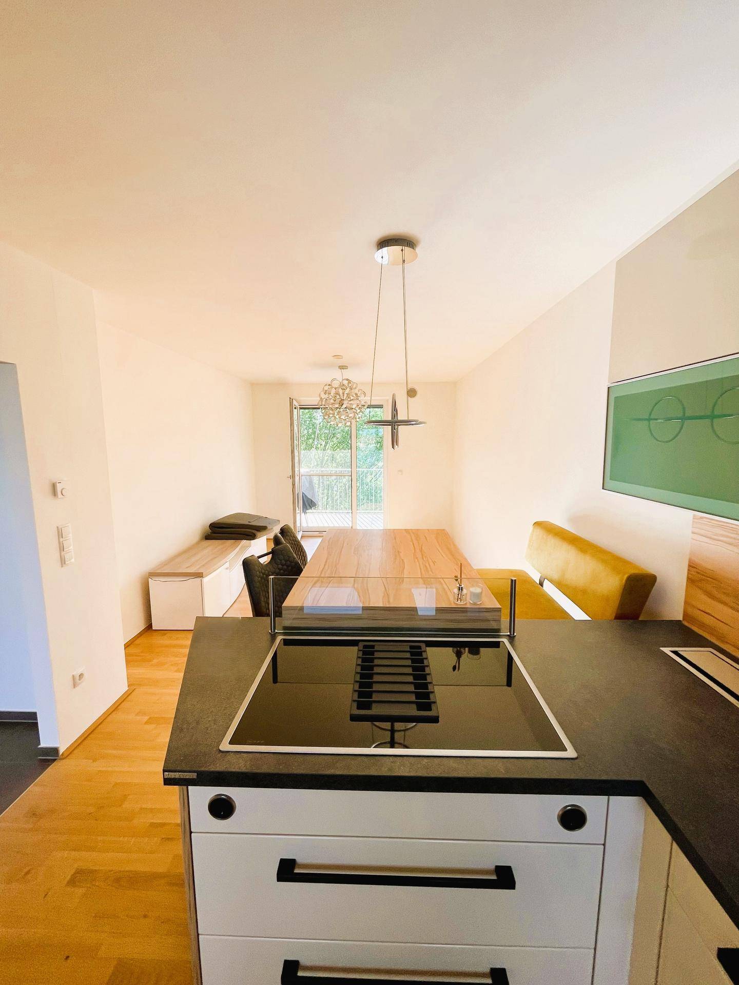 Moderne Küche mit Induktionskochfeld und Essbereich, ausgestattet mit Holzboden und Sitzbank.