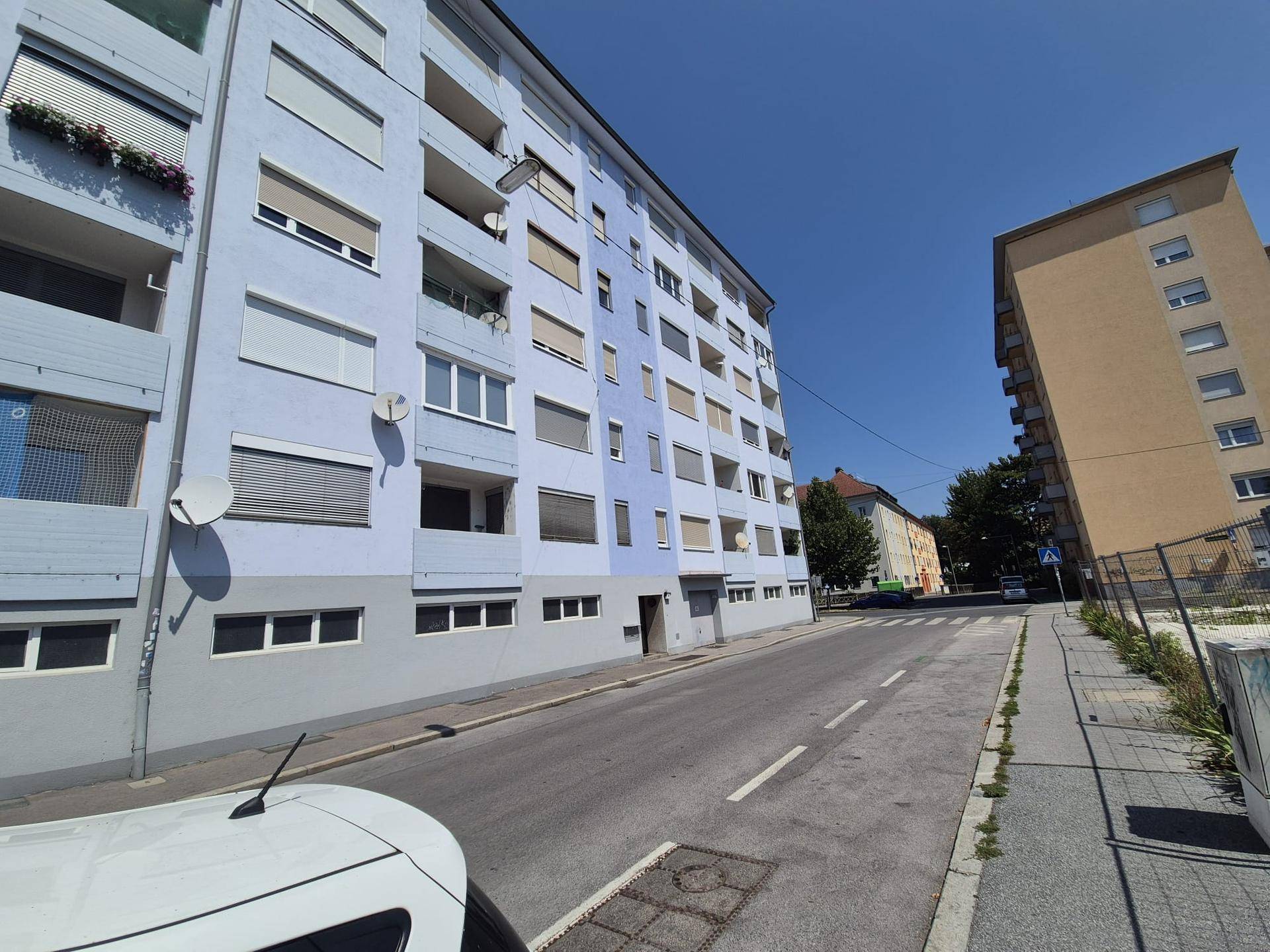 Fassade eines Wohngebäudes mit Balkonen und Rollläden an einem sonnigen Tag.