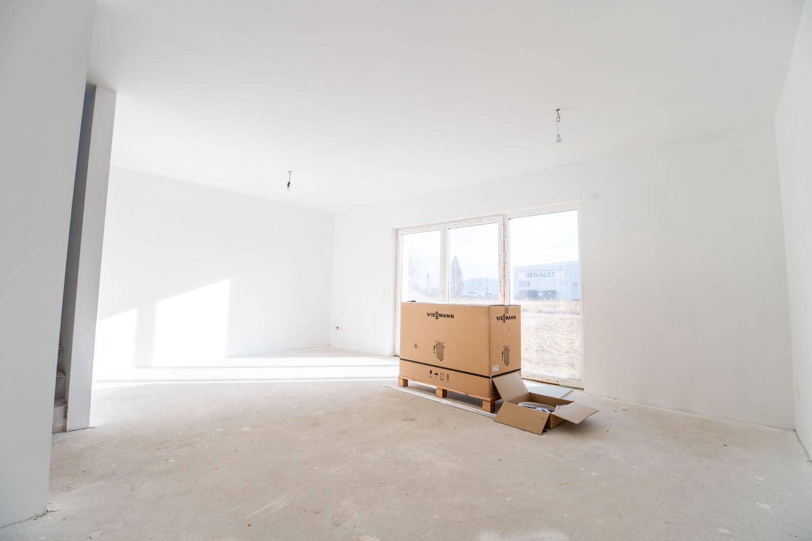 Heller Wohnbereich im Rohbau mit großen Fenstern und einer Viessmann-Verpackung.
