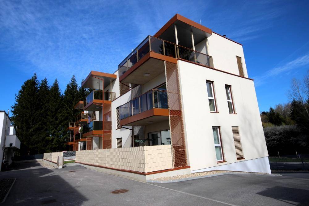 Moderne Wohnanlage mit mehreren Balkonen und zeitgenössischer Architektur unter blauem Himmel.