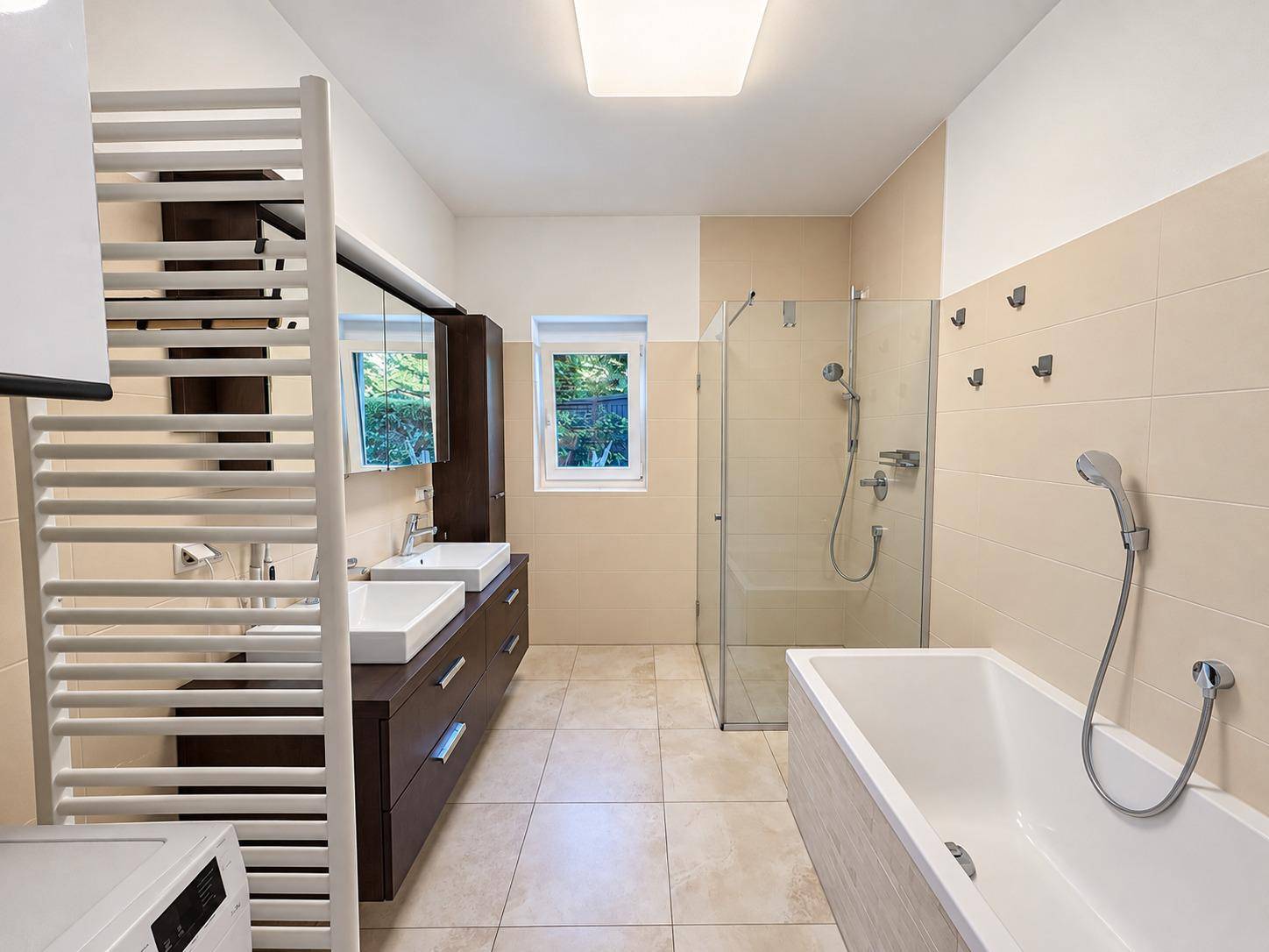 Modernes Badezimmer mit Badewanne, begehbarer Dusche, Doppelwaschbecken und Handtuchheizkörper.
