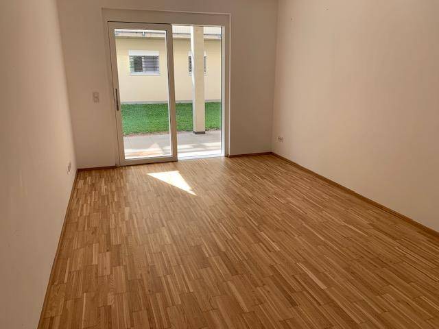 Leerer Raum mit hellem Laminatboden und Zugang zu einer Terrasse oder Garten.