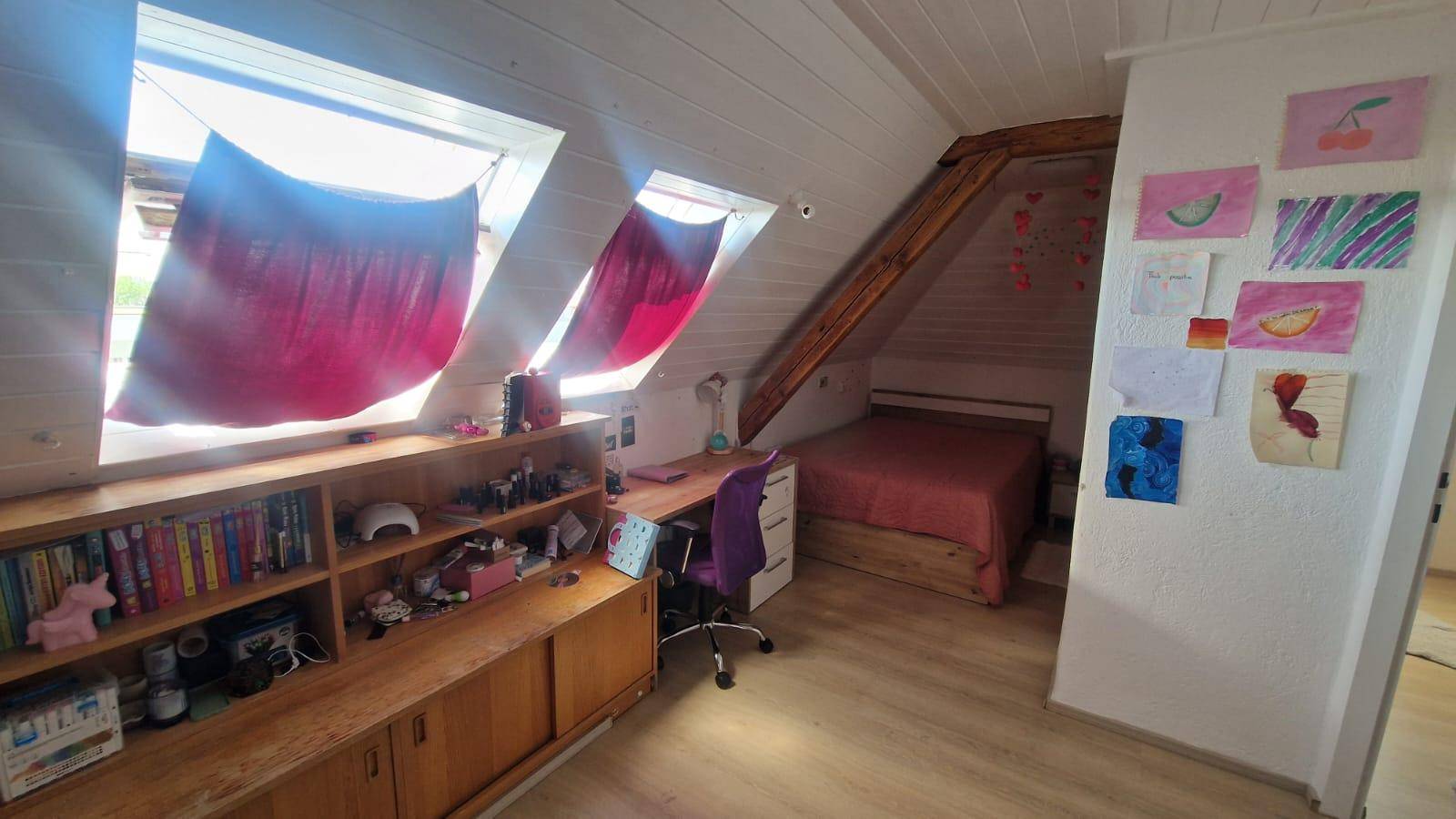 Helles Dachgeschoss-Schlafzimmer mit zwei Dachfenstern und integriertem Schreibtischbereich.