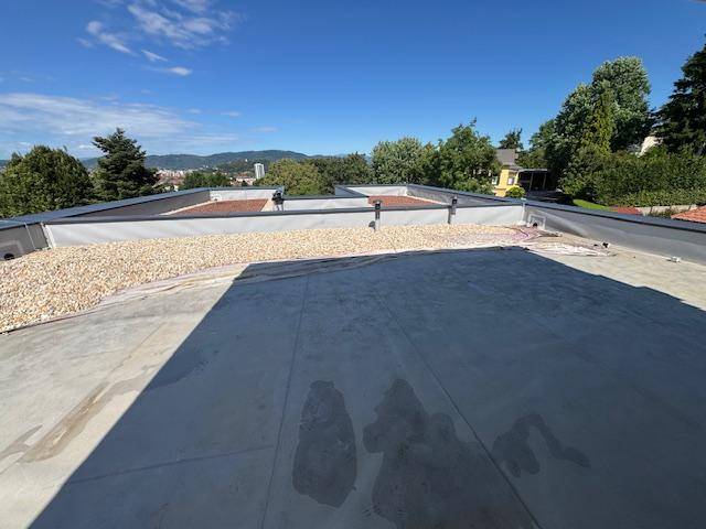 Dachfläche in Bau mit Kiesbelag und Vorbereitung für eine zukünftige Dachterrasse.