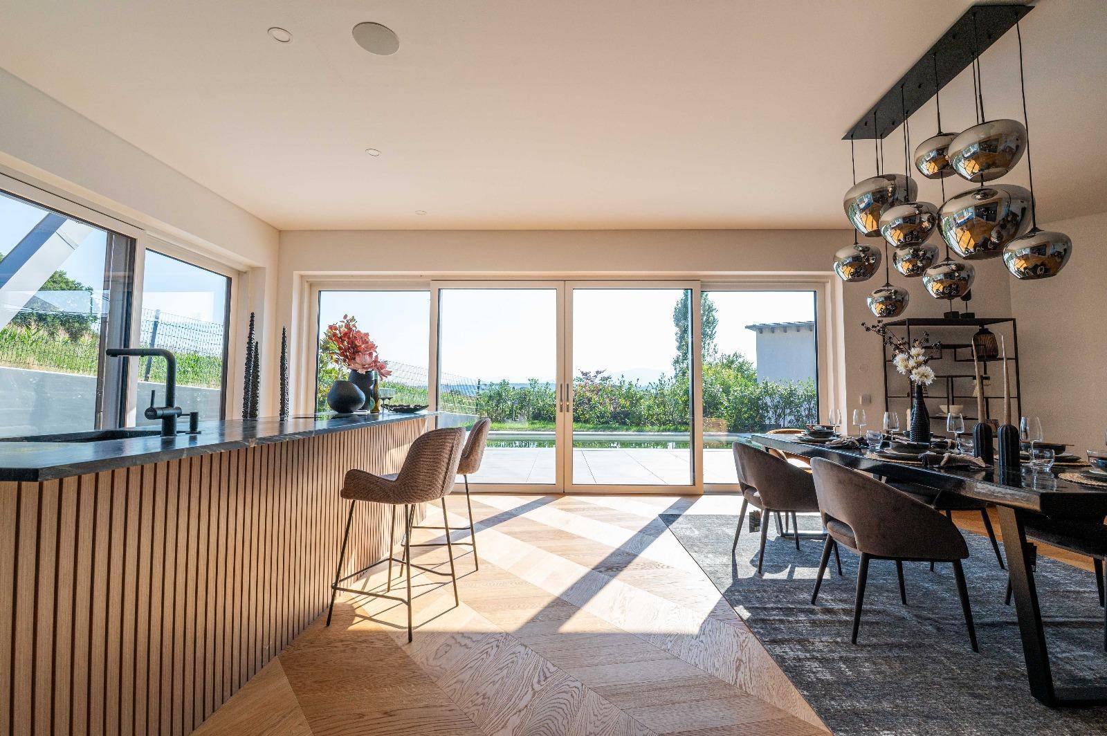 Moderne Kücheninsel mit Barhockern und weitem Blick durch die Panoramafenster.