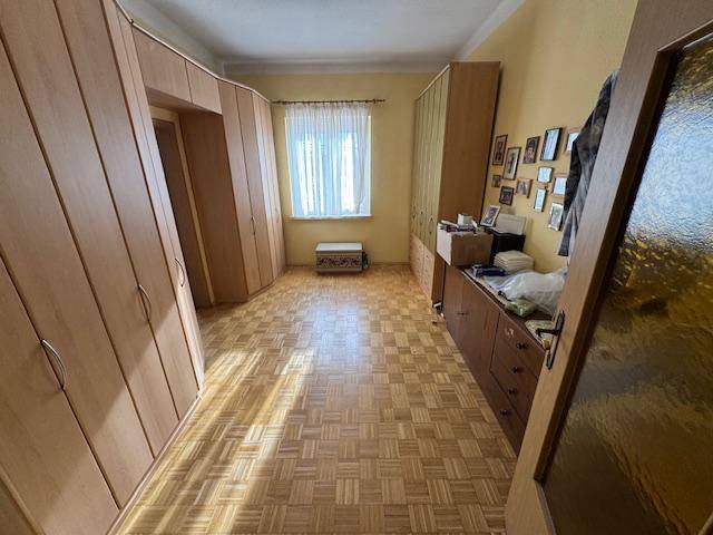Schlafzimmer mit Parkettboden und großen, hellen Holzschränken entlang der Wände.