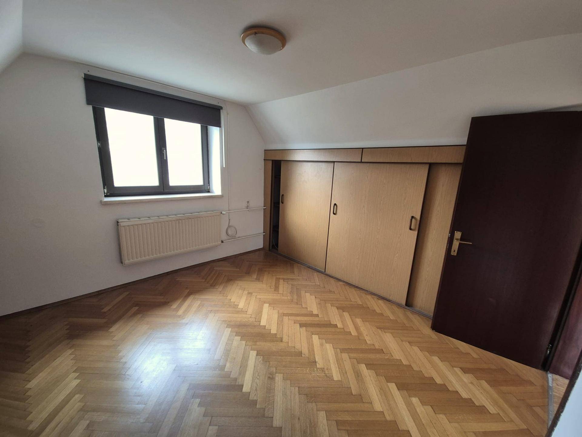 Schlafzimmer mit praktischen Einbauschränken und klassischem Fischgrätparkett.