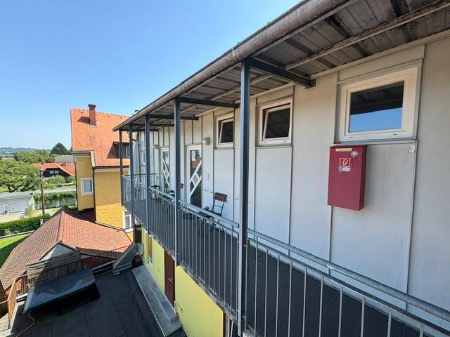 Langer Außenbalkon mit Metallgeländer, der Zugang zu mehreren Wohneinheiten bietet.