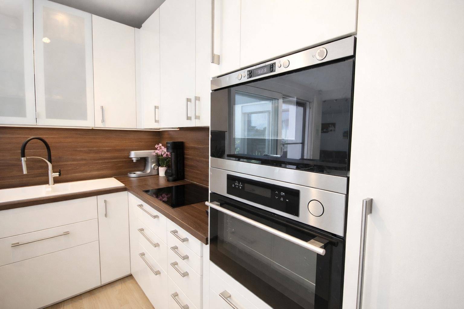 Hochwertige Einbaugeräte in der Küche, darunter Backofen und Mikrowelle in modernem Design.