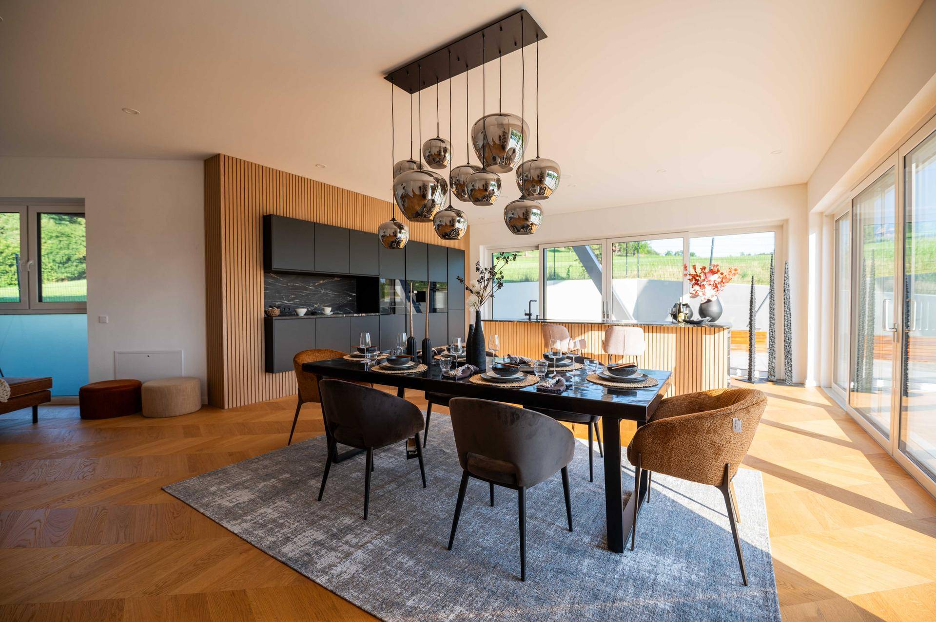 Eleganter Essbereich mit Designerleuchte, Fischgrätparkett und Blick ins Grüne.