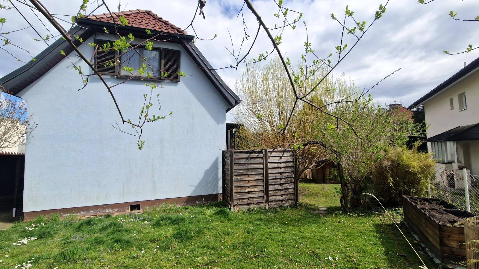 Seitenansicht des Hauses mit hellblauer Fassade und einem grünen Gartenbereich.