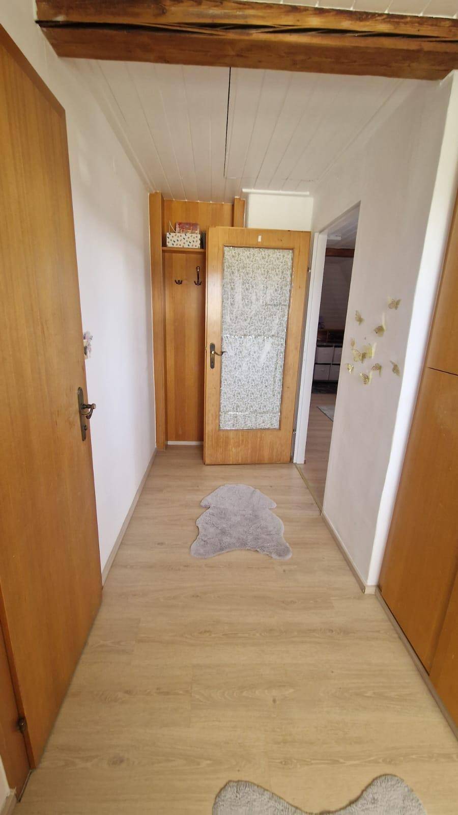 Heller Flur mit Holzboden und Türen, charakterisiert durch einen sichtbaren Holzdeckenbalken.
