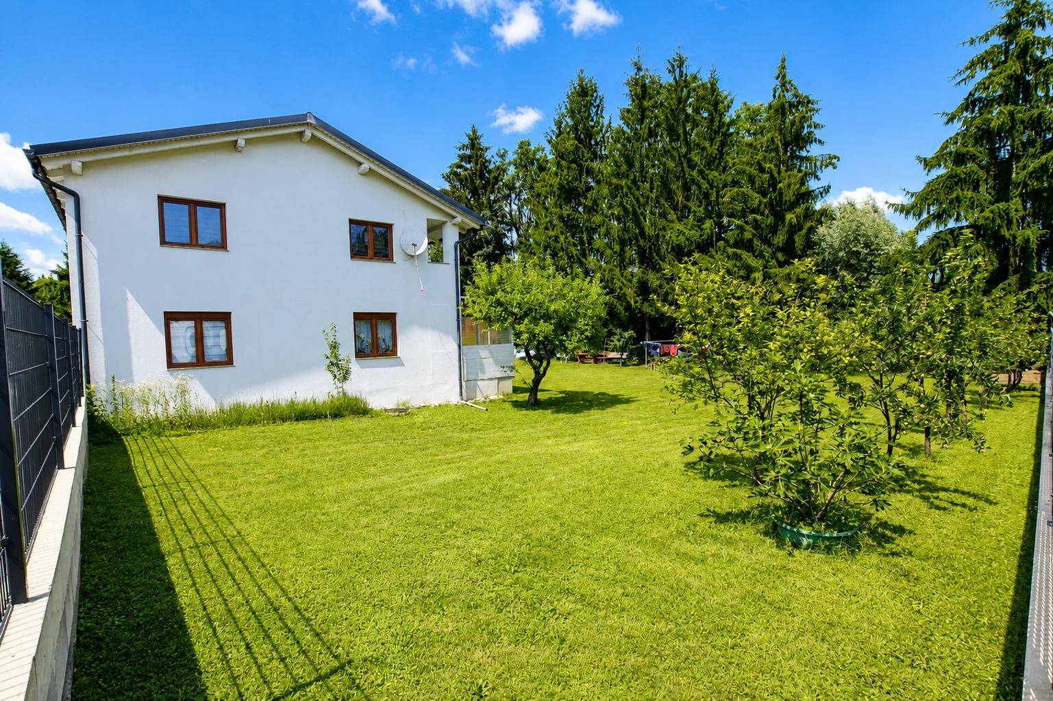 Großer, sonniger Gartenbereich mit Rasenfläche und Blick auf die Rückseite des Hauses.