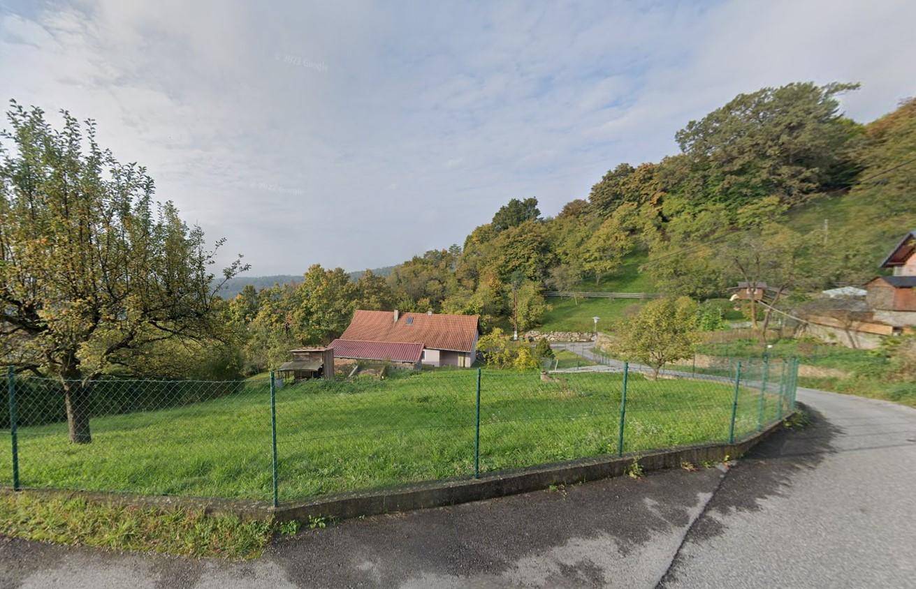 Grünes Grundstück an einer Straße mit einem traditionellen Haus und weitem Blick auf die umliegende Landschaft.