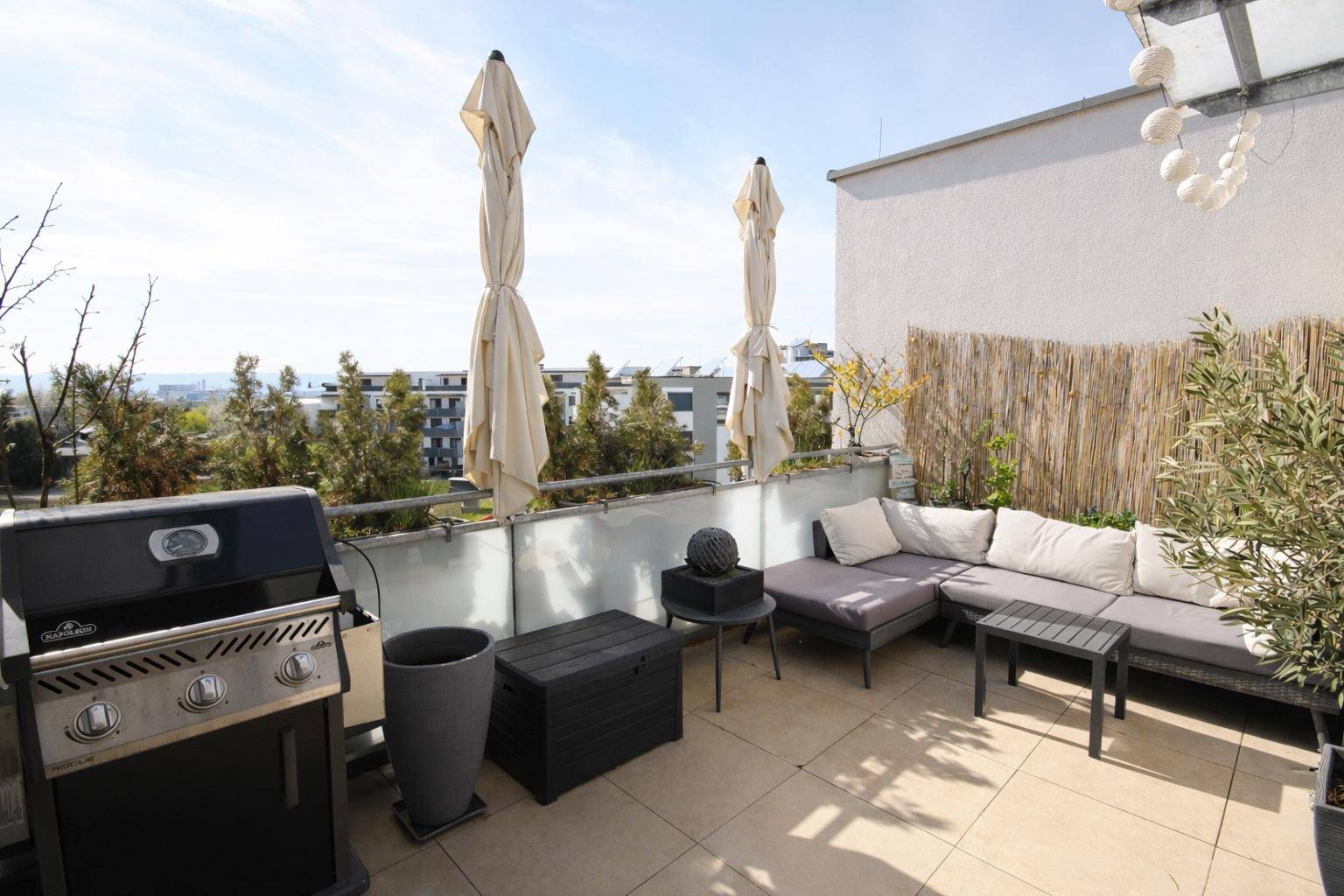 Geräumige Terrasse mit Grillbereich, Loungemöbeln und Sonnenschirmen für entspannte Stunden.
