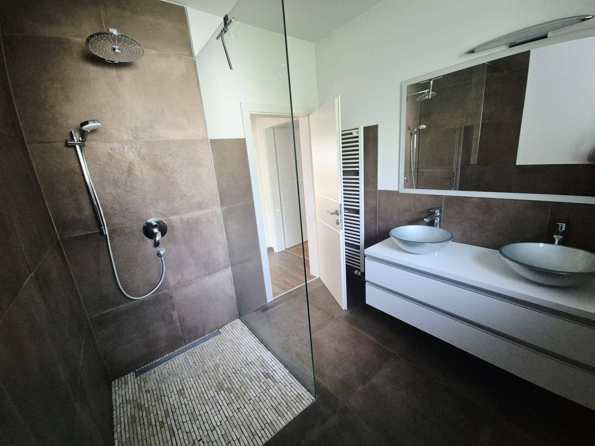 Elegantes Badezimmer mit ebenerdiger Dusche, Regendusche und modernen Armaturen.