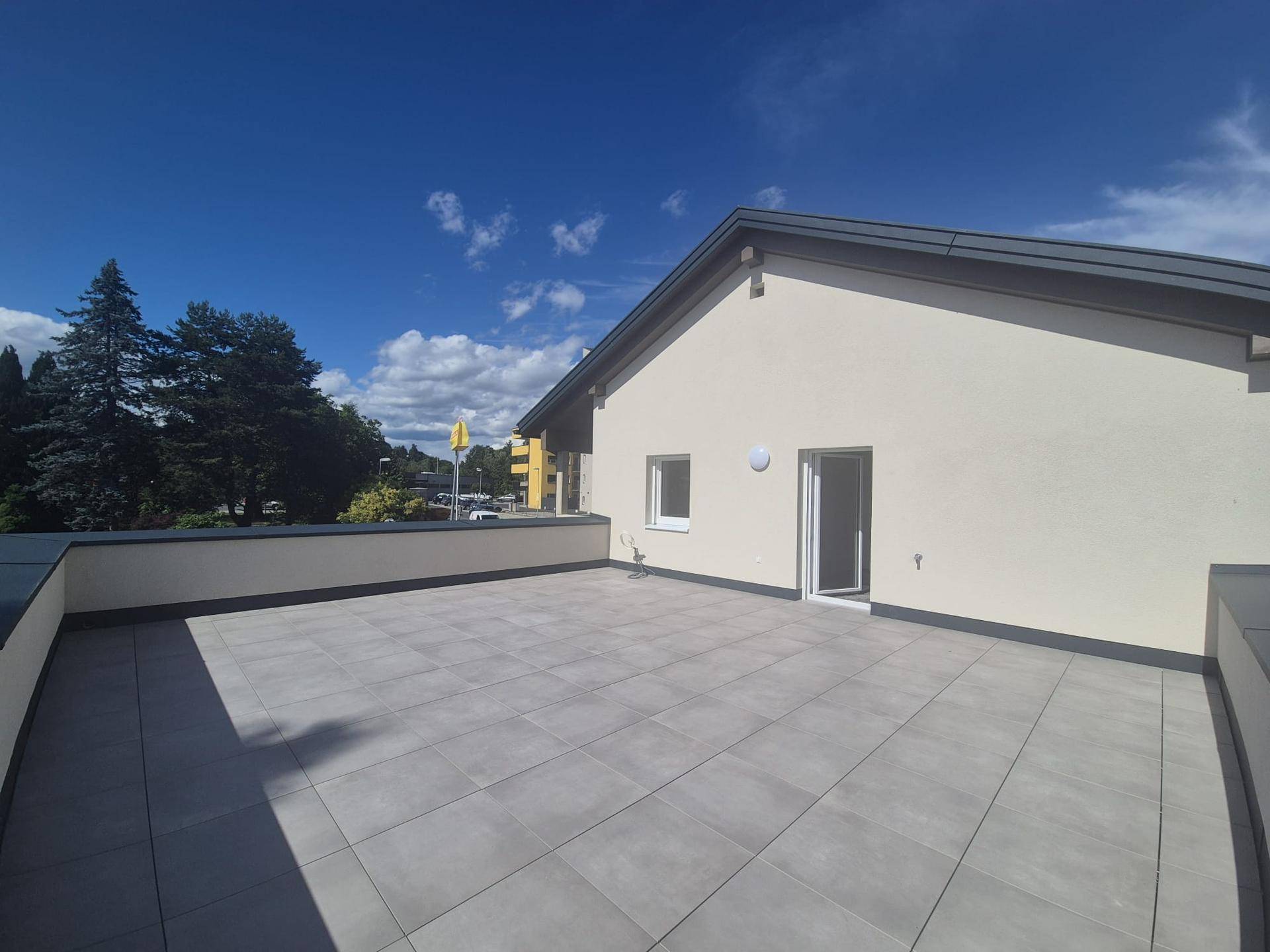 Sonnige Dachterrasse mit Zugang zum Innenbereich und Blick auf die umliegende Landschaft.