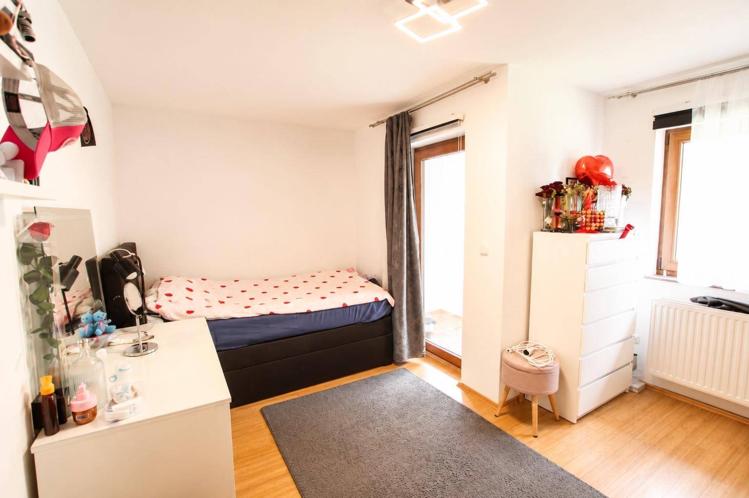 Helles Schlafzimmer mit Einzelbett, Schminktisch und direktem Zugang zu einem Außenbereich.