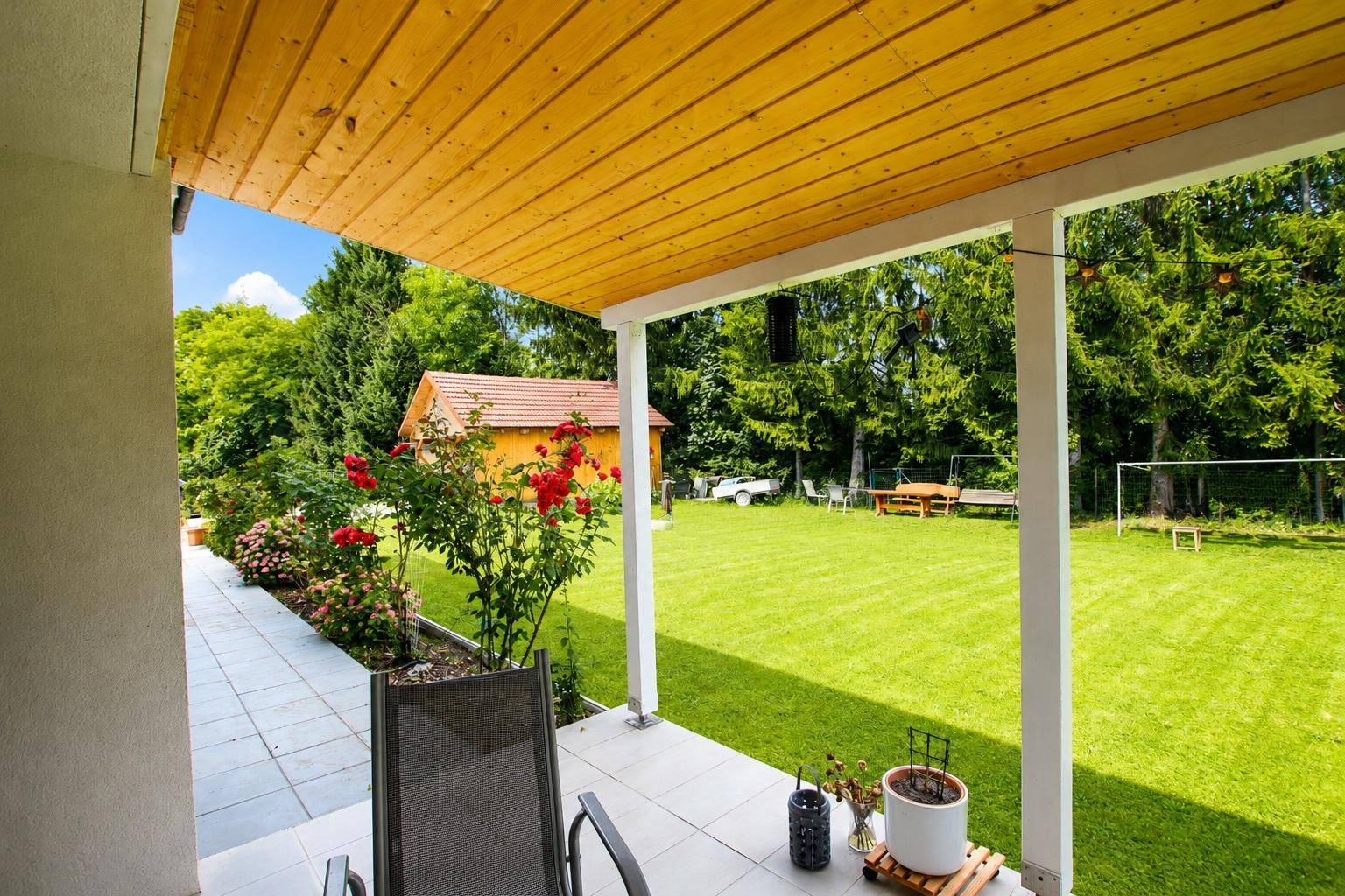 Geräumige überdachte Terrasse mit Holzdach und direktem Zugang zum Garten.