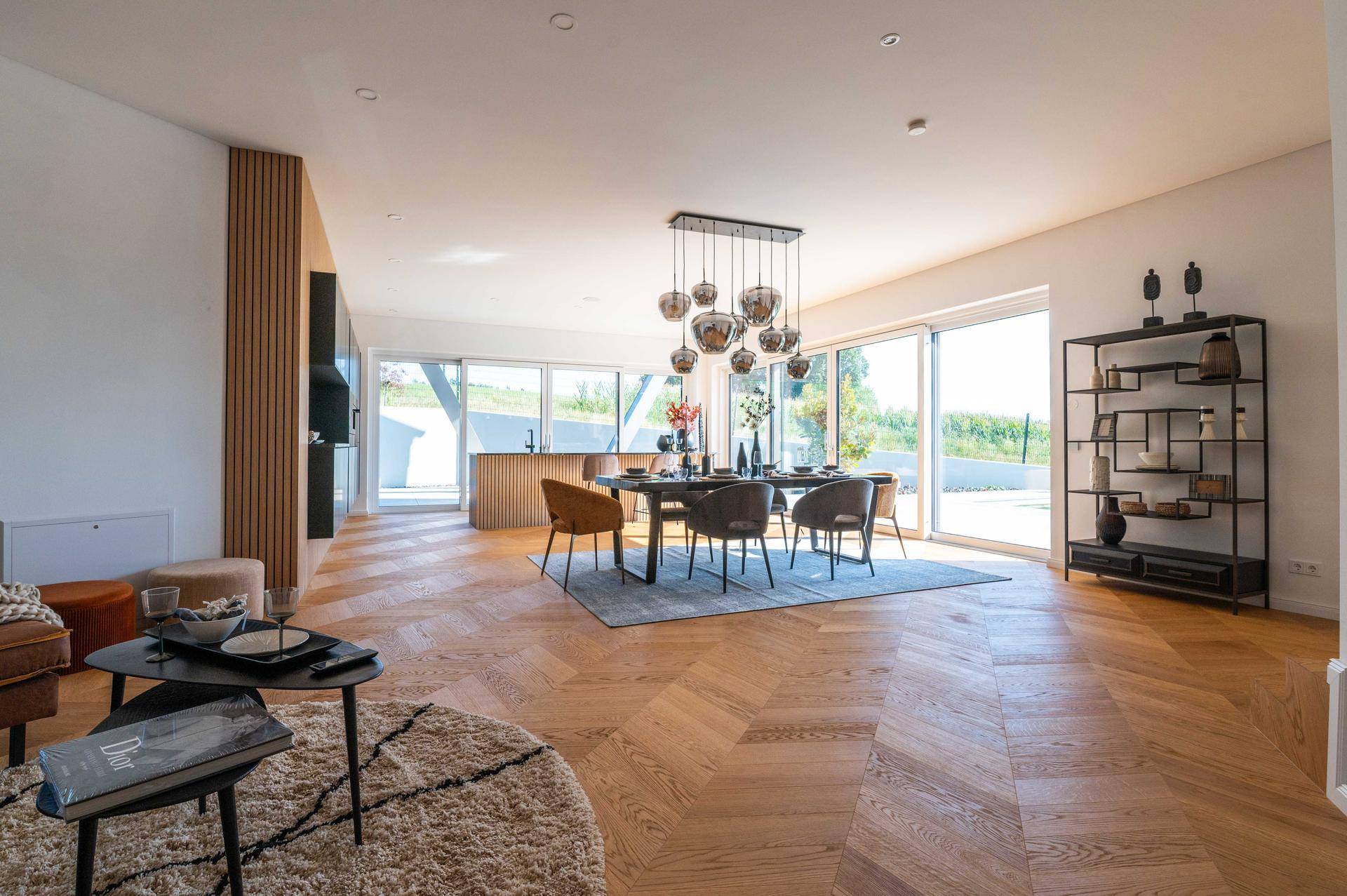 Geräumiger offener Wohn-Essbereich mit Küche, Holzboden und viel Tageslicht.