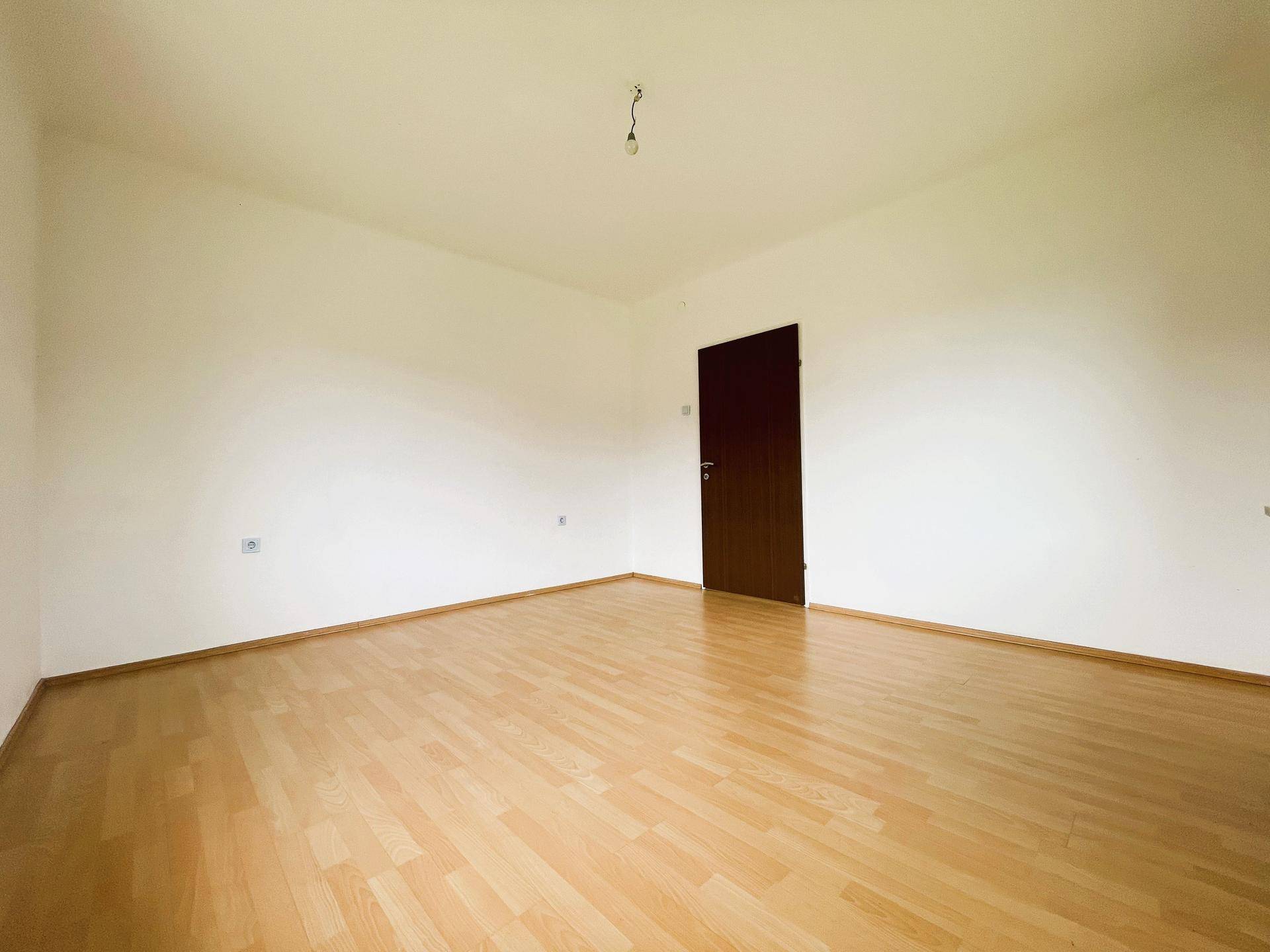 Heller, unmöblierter Raum mit Laminatboden, bereit für individuelle Gestaltung.
