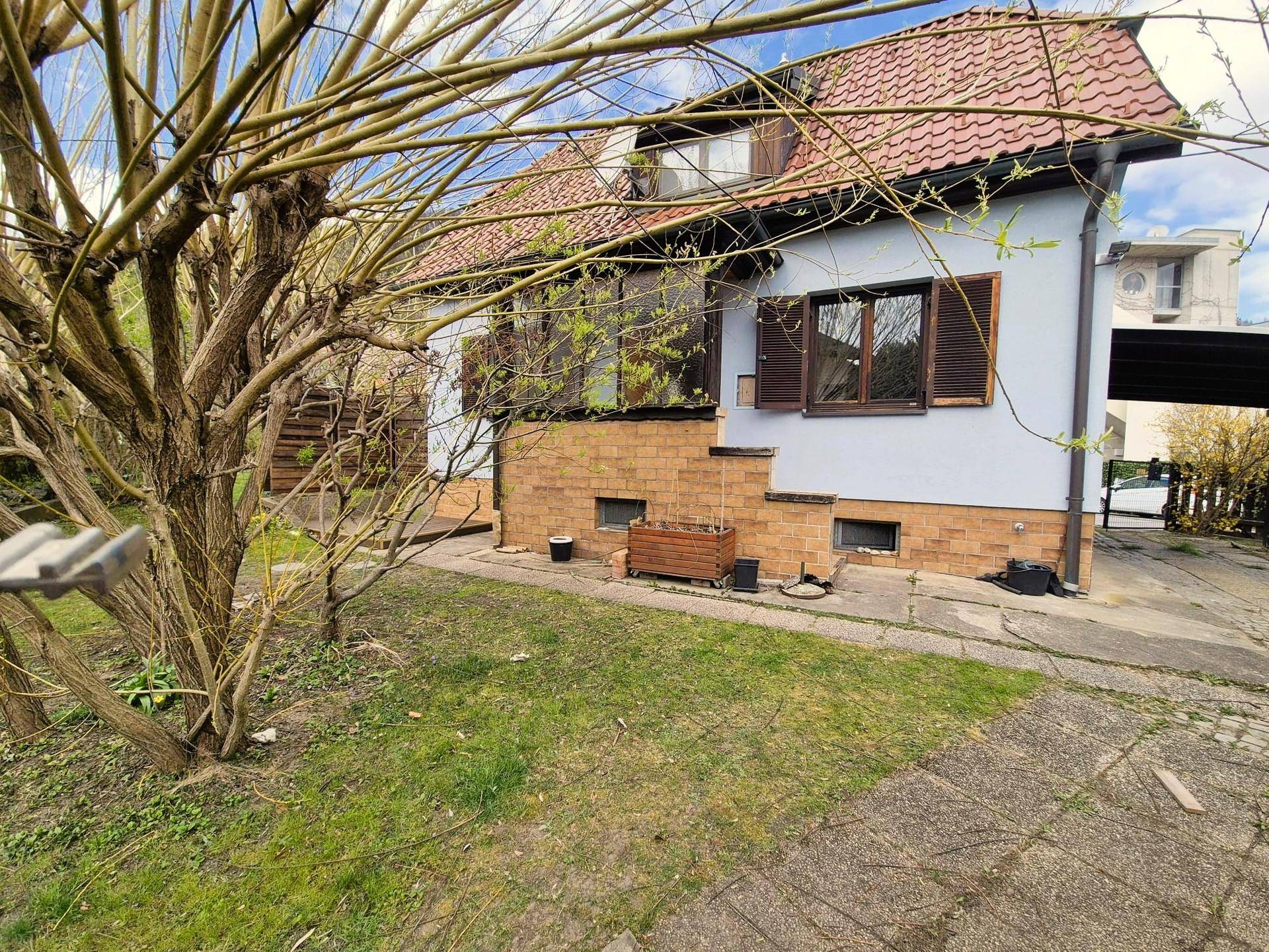 Charmantes Haus mit rotem Ziegeldach und einem gepflegten Gartenbereich im Vordergrund.