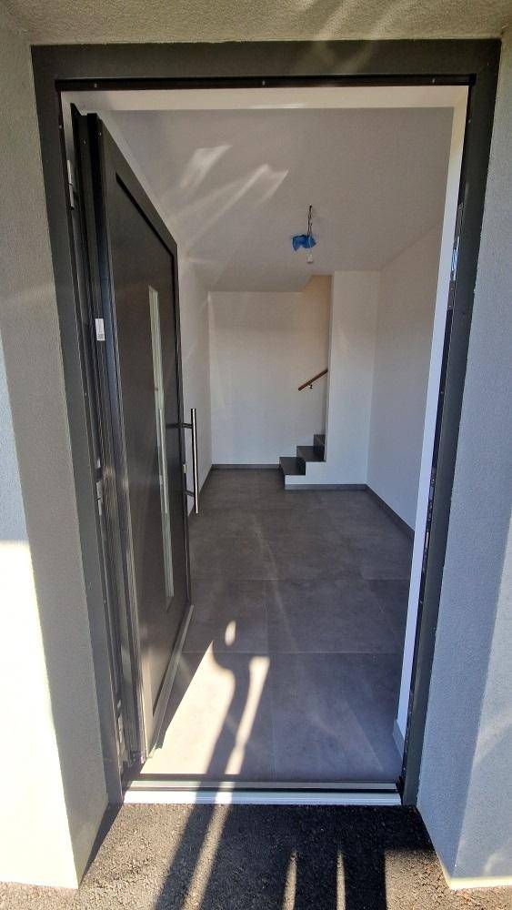 Heller Eingangsbereich mit dunklen Fliesen und Blick auf die Treppe ins Obergeschoss.