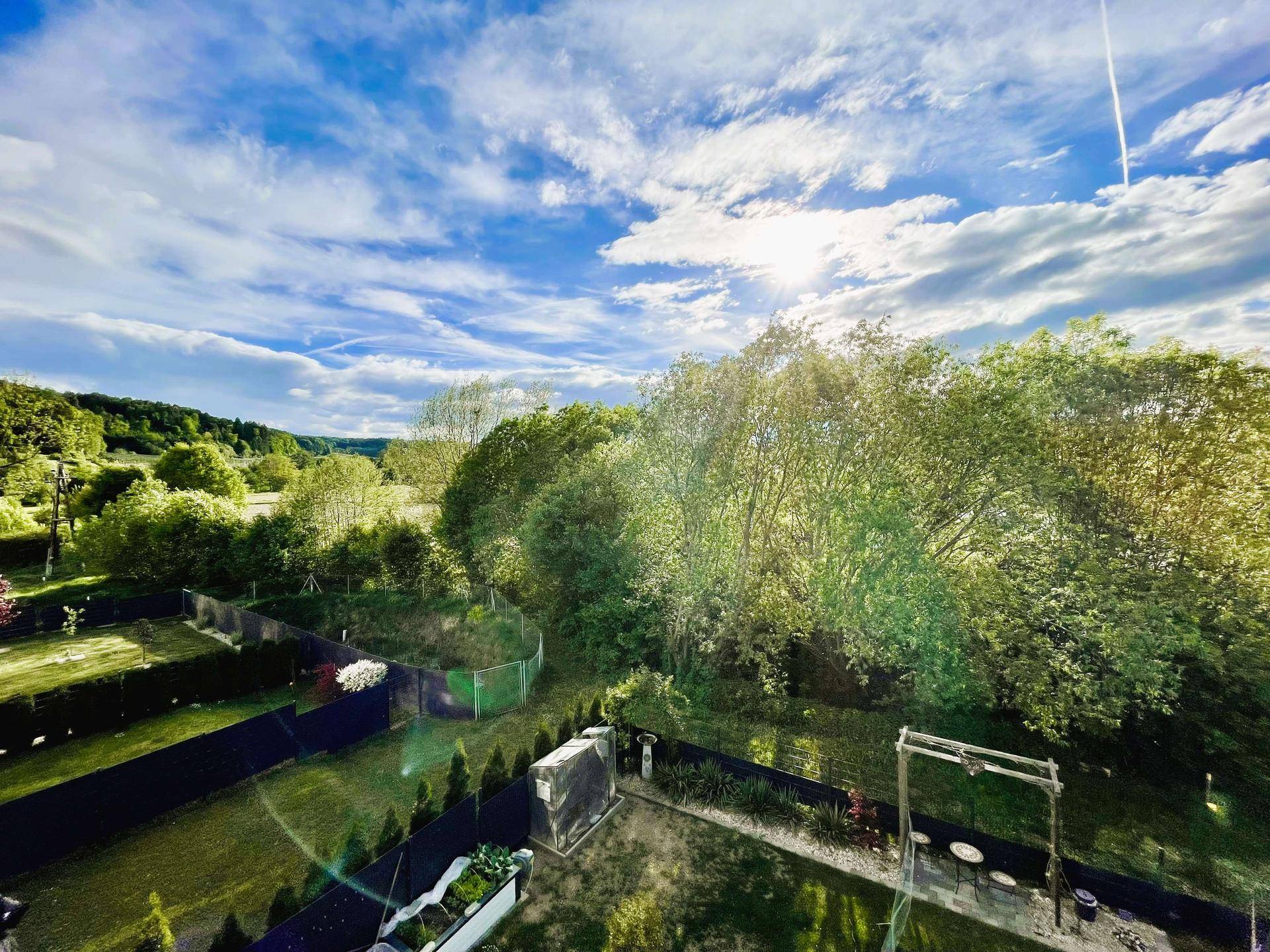 Weitläufiger Blick ins Grüne mit Gärten und Bäumen unter einem blauen Himmel.