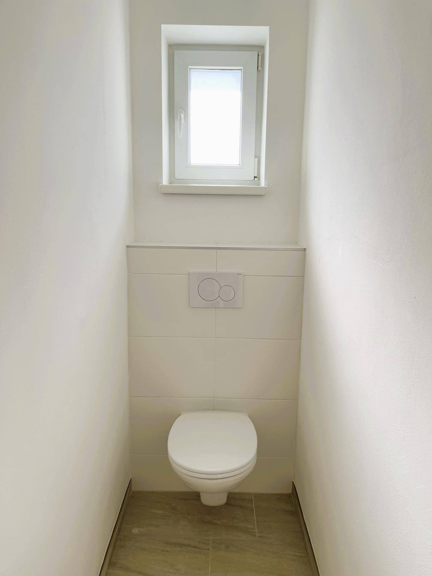 Separates WC mit Fenster und Wand-WC, hell und funktional gestaltet.