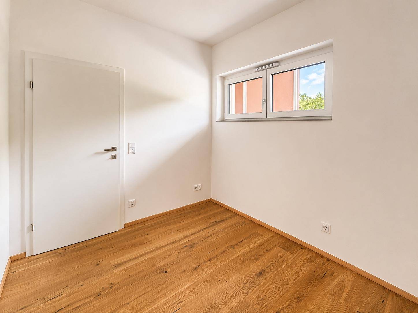 Geräumiges Zimmer mit Holzboden und einem Fenster, ideal als Schlaf- oder Arbeitszimmer.