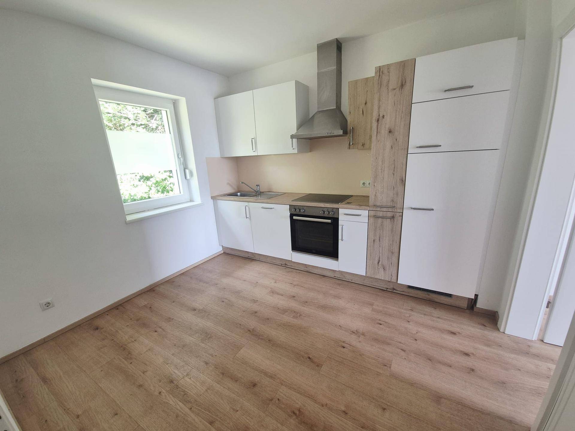 Moderne Einbauküche mit weißen und holzfarbenen Fronten, ausgestattet mit Herd und Dunstabzug.