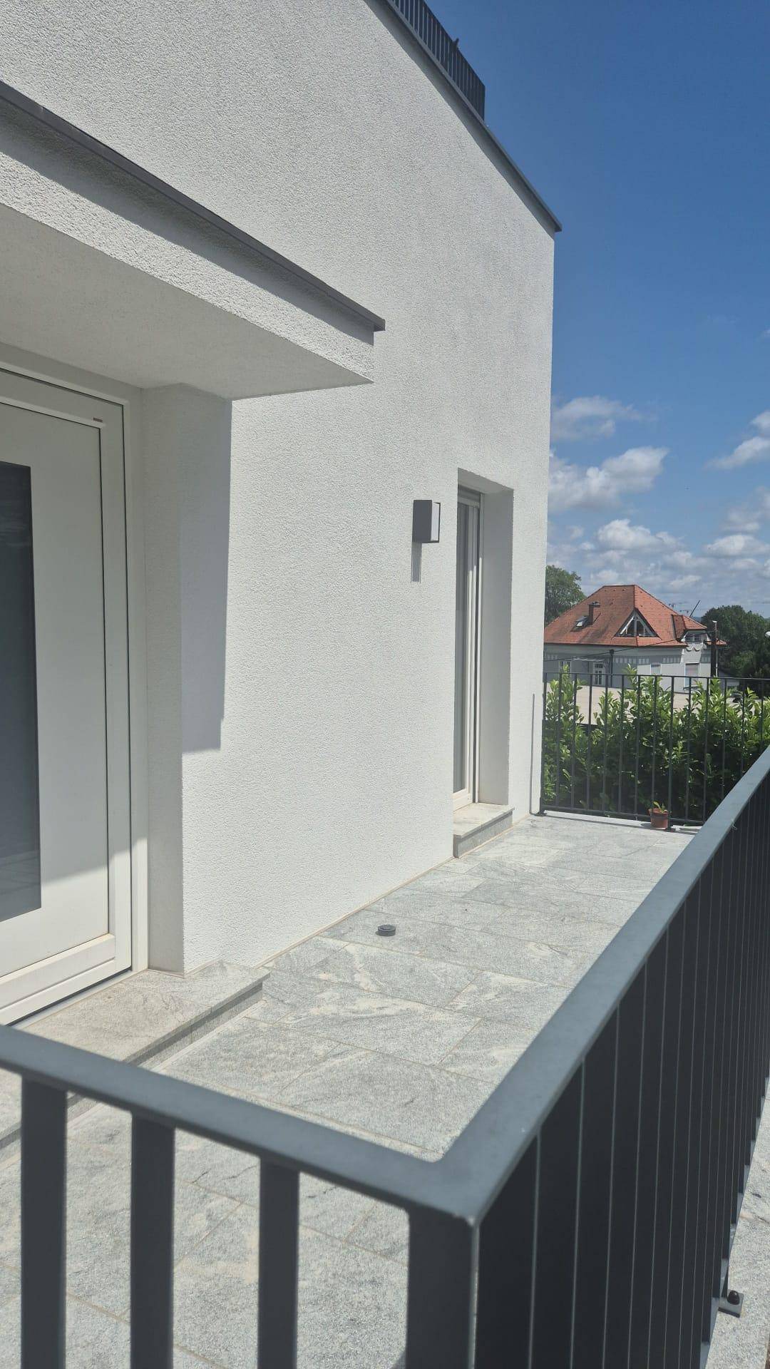 Heller Balkon mit modernen Fliesen und Blick auf die Umgebung unter blauem Himmel.