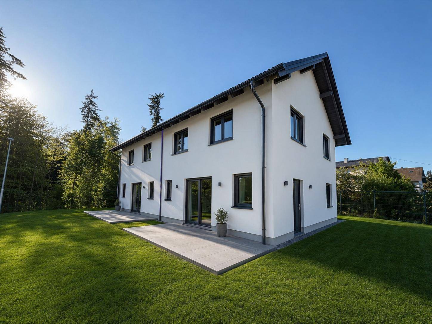 Rückansicht der modernen Doppelhaushälfte mit weitläufigem Garten und sonniger Terrasse.