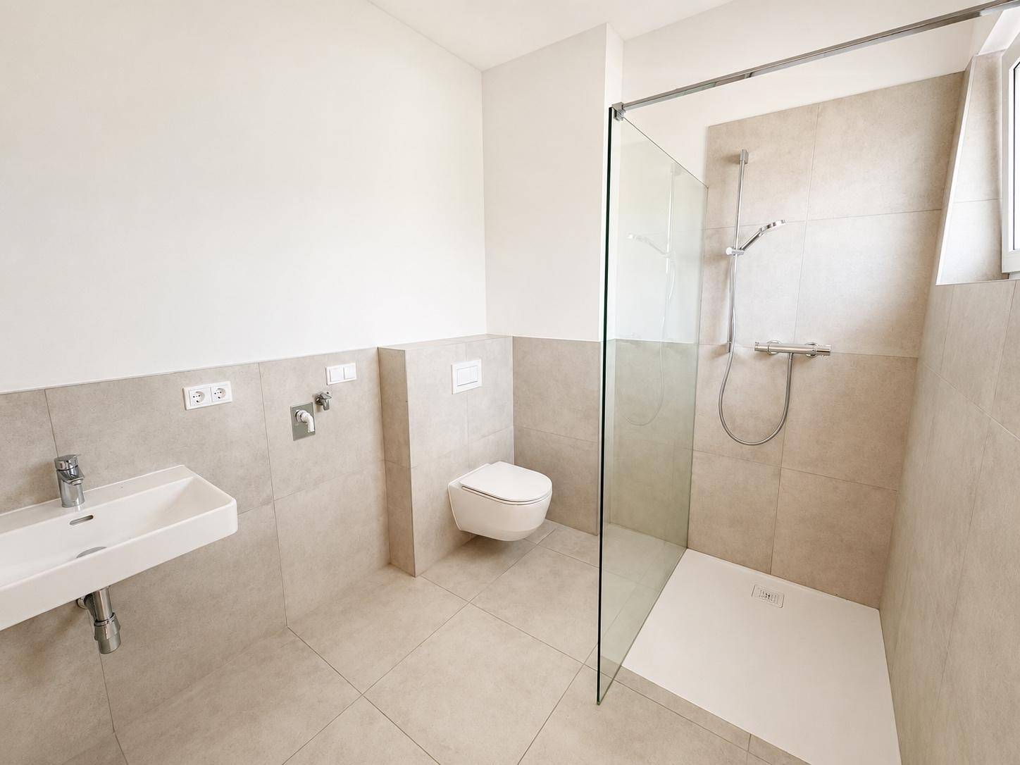 Modernes Badezimmer mit begehbarer Dusche, Wand-WC und hellen Fliesen.