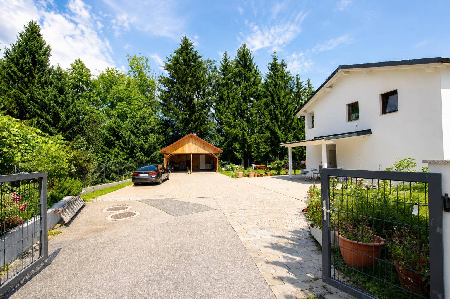 Zufahrt zum Haus mit großem Carport und gepflegtem Vorgartenbereich.