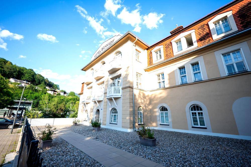 Historisches Gebäude mit Eingangsbereich, Kiesweg und blühenden Pflanzen.