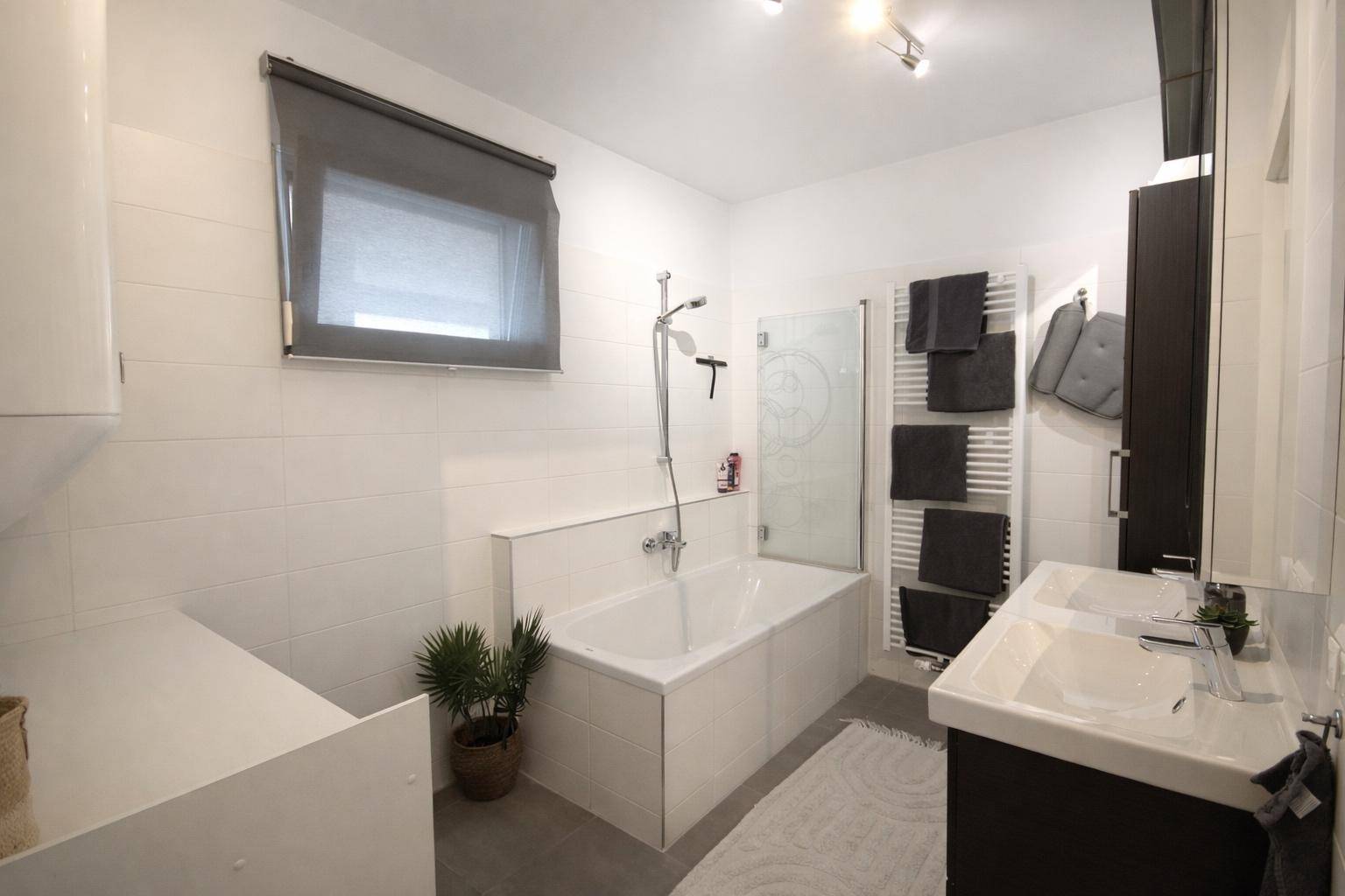 Modernes Badezimmer mit Badewanne, Dusche, Doppelwaschbecken und beheiztem Handtuchhalter.