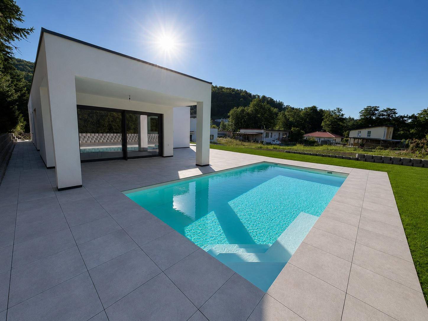 Sonniger Poolbereich mit breiten Stufen und einer überdachten Terrasse am modernen Bungalow.