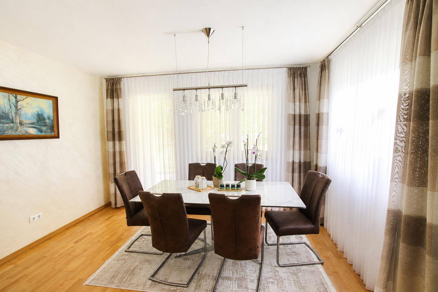 Eleganter Essbereich mit großem Esstisch, modernen Stühlen und viel Tageslicht.