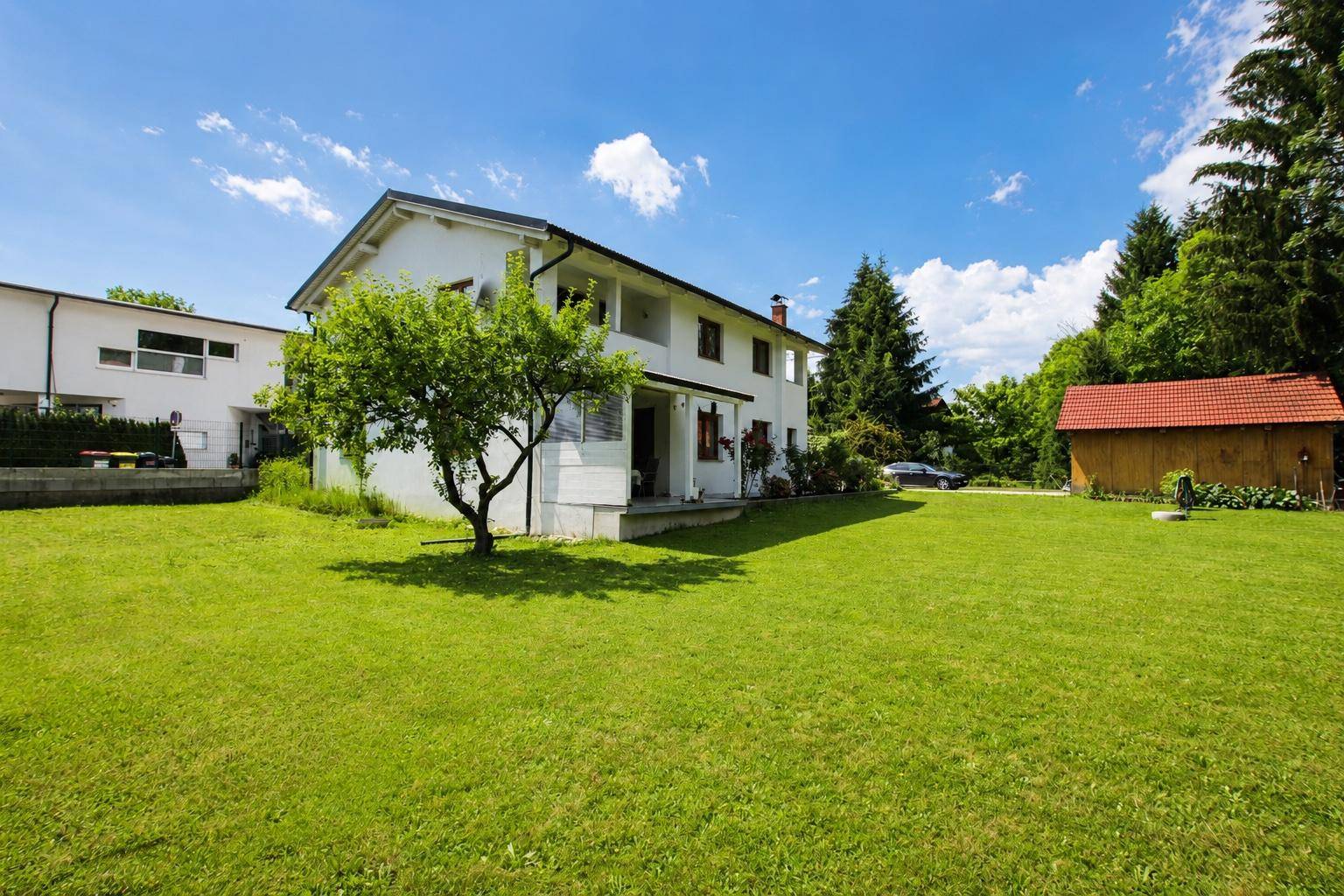 Weitläufiger Garten mit altem Baumbestand und Blick auf die Hausfassade.