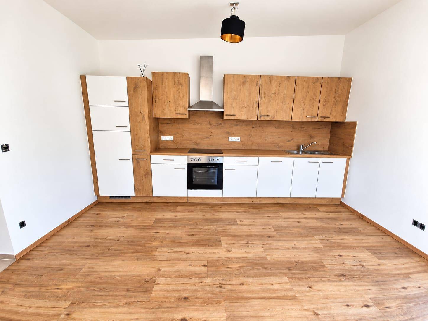 Moderne Einbauküche mit hellen Holzfronten und weißen Unterschränken, ausgestattet mit Backofen und Dunstabzug.