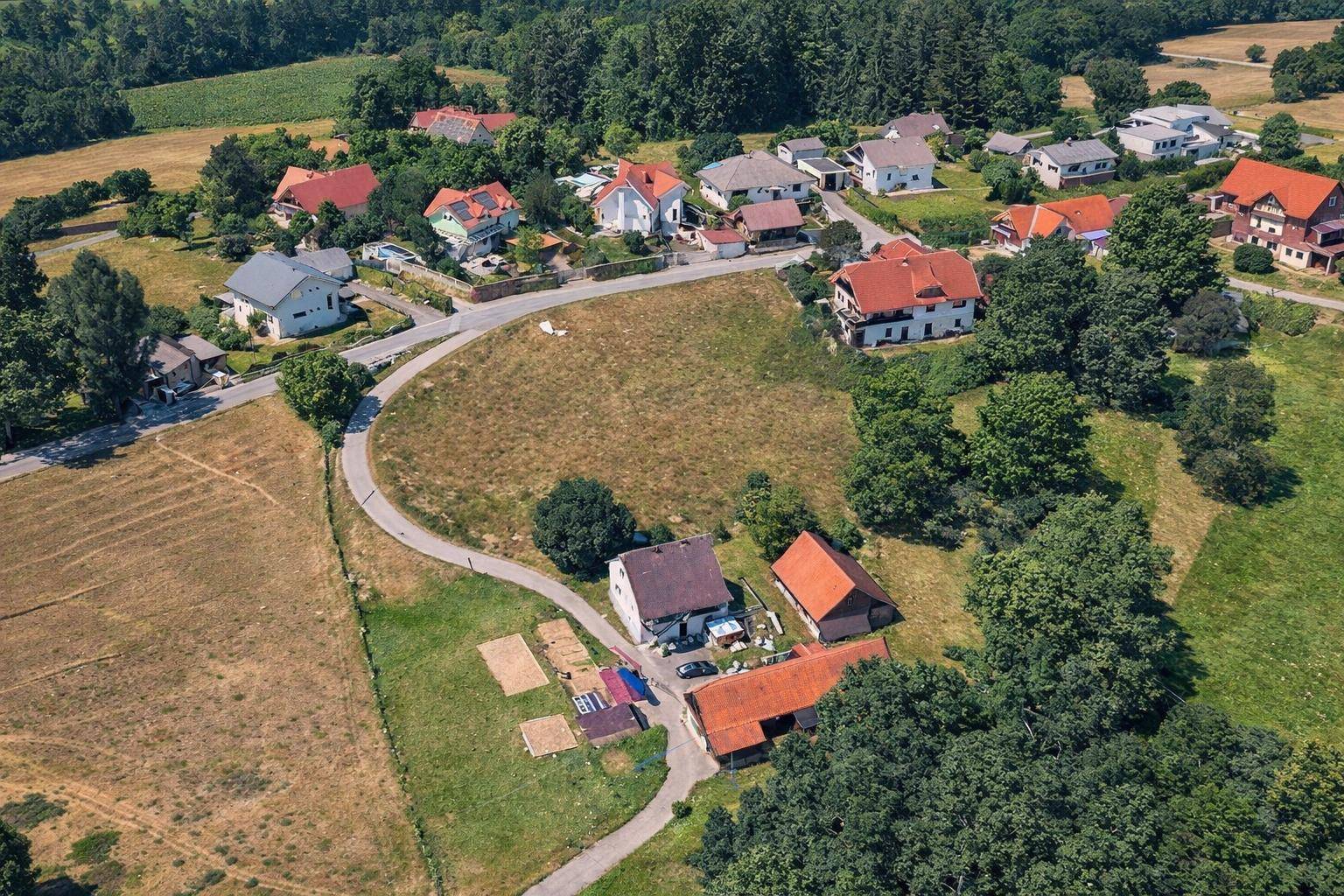 Weitläufige Luftaufnahme einer ländlichen Siedlung mit Feldern, Straßen und mehreren Wohnhäusern.